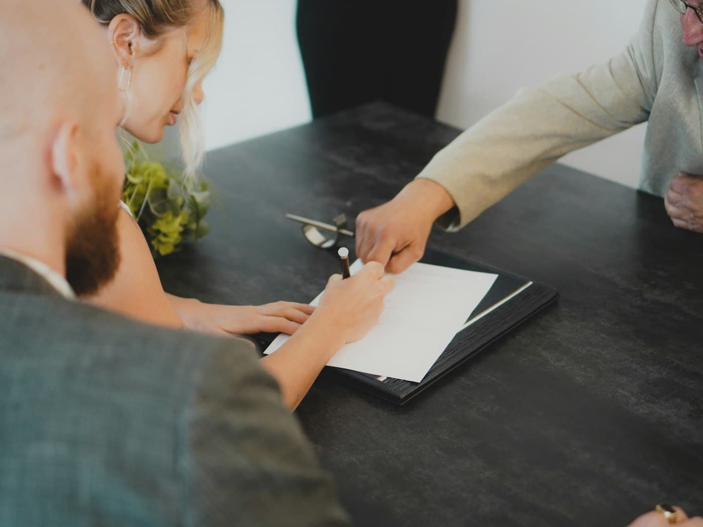Two people completing and signing loan paperwork at a desk